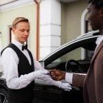 Professional doorman providing guest arrival assistance at a hotel entrance.