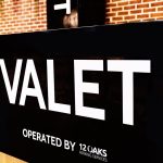 Valet service sign reading “VALET” with 12 Oaks branding displayed at a parking location