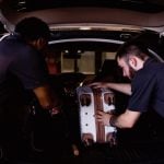 Doorman Bellman Services Workers loading luggage into a car from a hotel cart.