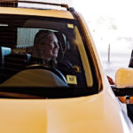 Valet attendant greeting a driver at a covered parking entrance while assisting with vehicle drop-off.