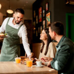 Restaurant server delivering a meal to guests enjoying an casual dining experience after arriving with valet parking.
