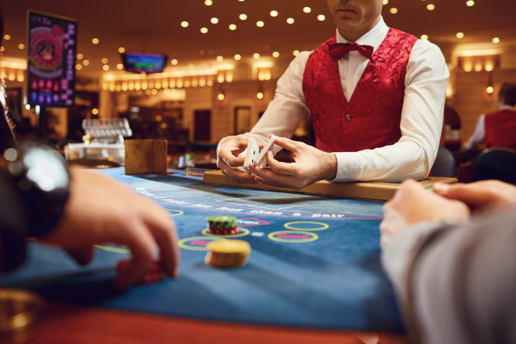 Casino dealer managing a live table game as guests play cards on the gaming floor of an upscale casino.