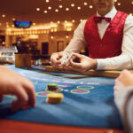 Casino dealer managing a live table game as guests play cards on the gaming floor of an upscale casino.