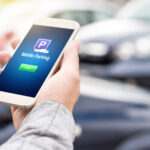 Driver using a smartphone mobile parking payment app while parked in a commercial parking lot.
