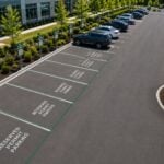 Aerial view of a commercial parking lot with reserved permit parking spaces, mobile payment signs for parking enforcement compliance.