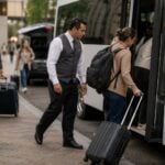 Guest services attendant assisting travelers and coordinating shuttle departures at a property entrance.