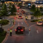 Parking attendants direct vehicles through organized entrances and exits at a busy event venue, maintaining safe traffic flow and efficient vehicle circulation during peak arrivals.